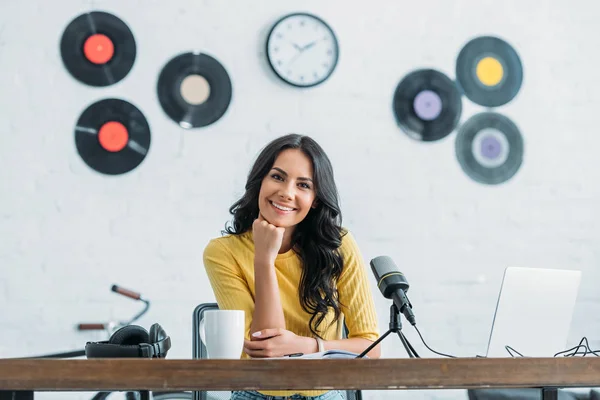 Attraktiv Radiovært Smiler Til Kameraet Mens Sidder Arbejdspladsen Radiostudie - Stock-foto