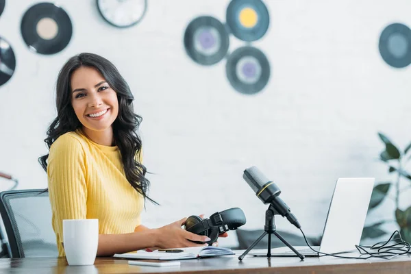 Neşeli Radyo Host Işyerinde Otururken Kulaklık Tutarak Kameraya Gülümseyen — Stok fotoğraf