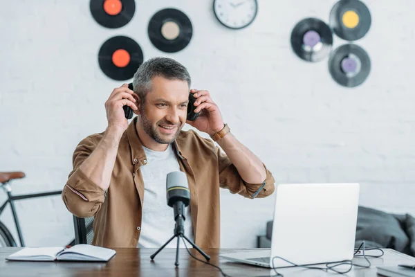 Handsome Radiovärd Tittar Laptop Medan Sitter Arbetsplatsen Och Sätta Hörlurar — Stockfoto