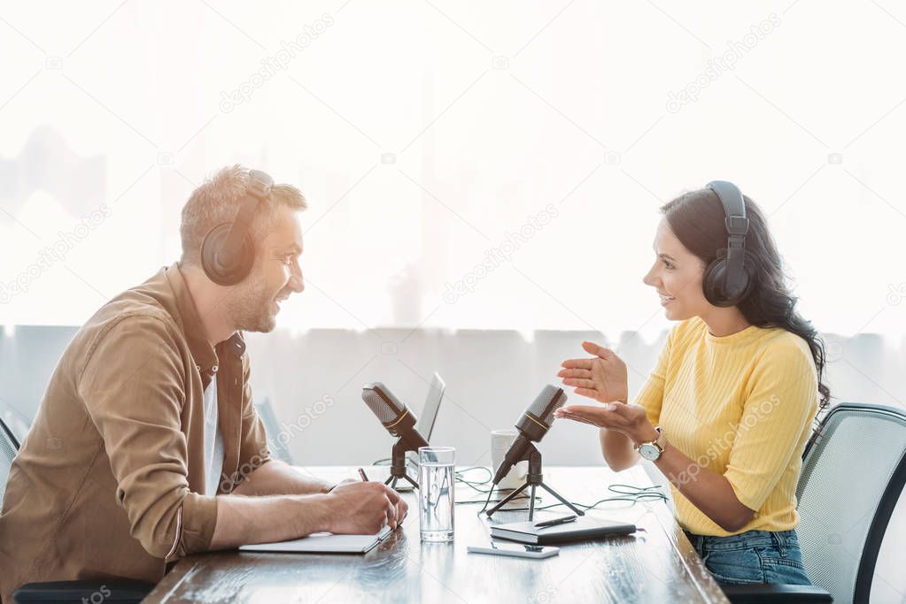 two smiling radio hosts talking while recording podcast in broadcasting studio