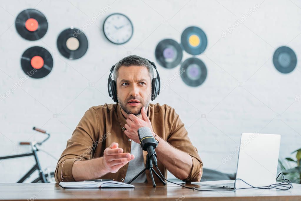 thoughtful radio host in headphones recording podcast in broadcasting studio