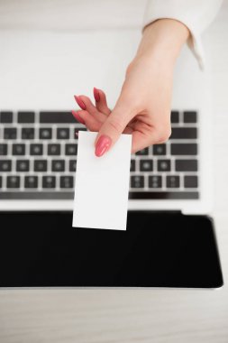 dizüstü bilgisayarın yanında beyaz boş kartvizit tutan iş kadını üst görünümü 