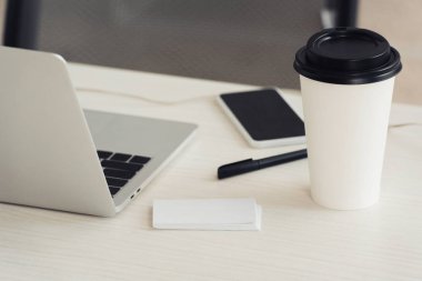 beyaz boş kartvizitler, dizüstü bilgisayar, gitmek için kahve, ofis masasında boş ekran ile kalem ve akıllı telefon