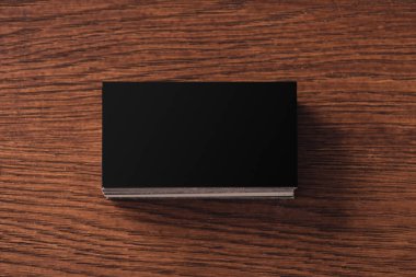 kahverengi ahşap masa üzerinde yığılmış siyah boş kartvizit üst görünümü
