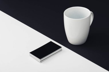 white coffee cup and black empty business cards on black and white background clipart
