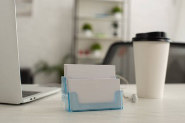 kağıt bardak ve ofis masasında dizüstü bilgisayar yanında beyaz boş kartvizit ile kart sahibi