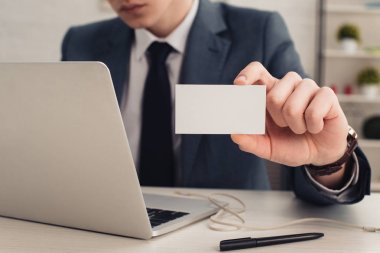 dizüstü bilgisayar kullanırken beyaz kartvizit tutan işadamı kısmi görünümü