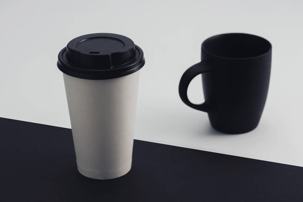 white paper cup and black coffee cup on black and white background