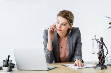 ciddi avukat ofiste oturan, uzak bakıyor ve akıllı telefon üzerinde konuşurken