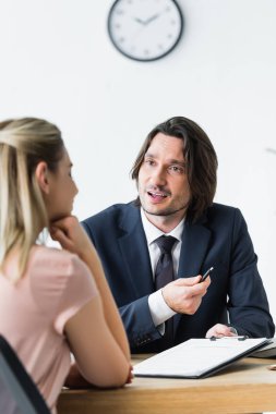 selective focus of businessman talking with client about contract clipart