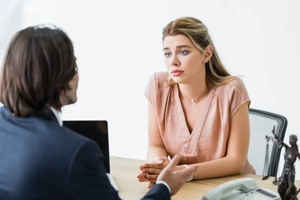 lawyer talking with upset woman sitting in office