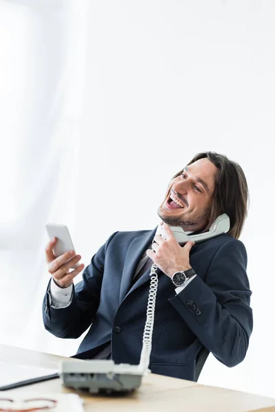 快乐英俊的商人在电话里聊天 手里拿着智能手机和耳机 — 图库照片