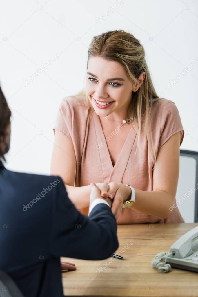 happy woman shaking hands with businessman in office