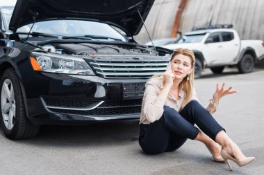 üzgün iş kadını akıllı telefon konuşuyor ve kırık otomatik yakınında oturan, araba sigortası konsept araba sigortası kavramı