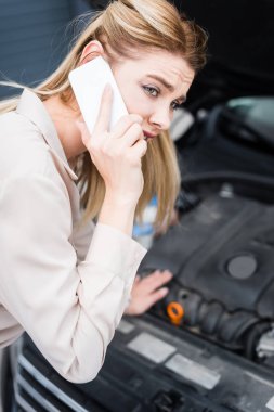 açık gövde, araba sigortası kavramı ile kırık otomatik yakın akıllı telefonda konuşurken üzgün iş kadını seçici odak