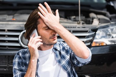 adam açık kaput ile kırık otomatik yakın akıllı telefonda konuşurken, baş el tutarak, araba sigortası kavramı