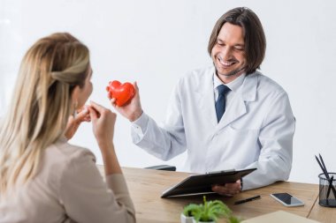 patient visiting doctor holding red heart and diagnosis in hands, medical insurance concept