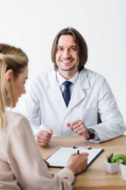 hasta ahşap masa arkasında doktor ile oturan ve imza belgesi