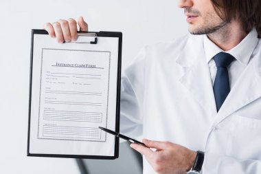 cropped view of doctor in white coat pointing with pen at medical document  clipart