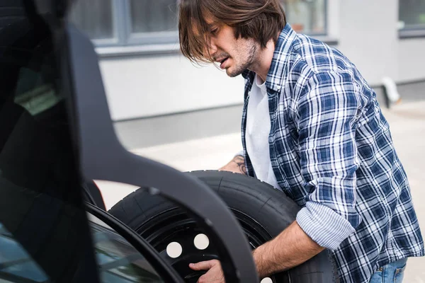 Mężczyzna Casual Nosić Koło Trzymania Rękach Pobliżu Auto Koncepcja Ubezpieczenia — Zdjęcie stockowe