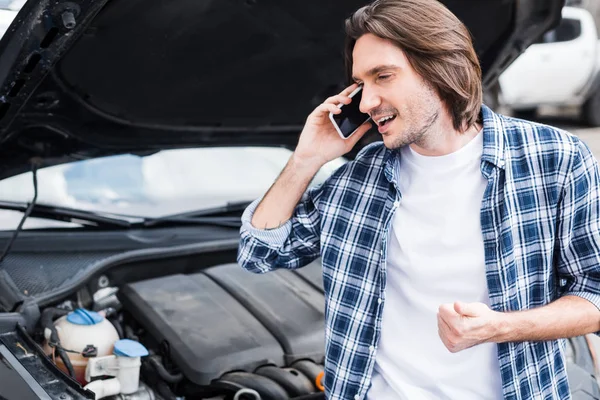 スマートフォンで話し オープントランクで壊れた自動車の近くに立っている幸せな男 自動車保険の概念 — ストック写真