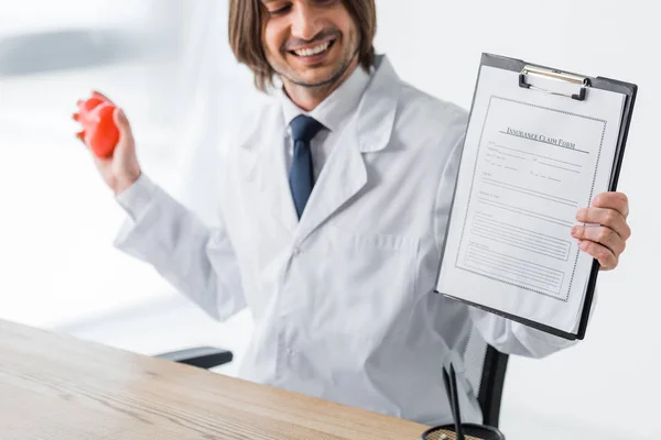 Feliz Médico Sosteniendo Corazón Rojo Formulario Reclamación Seguro Las Manos — Foto de Stock