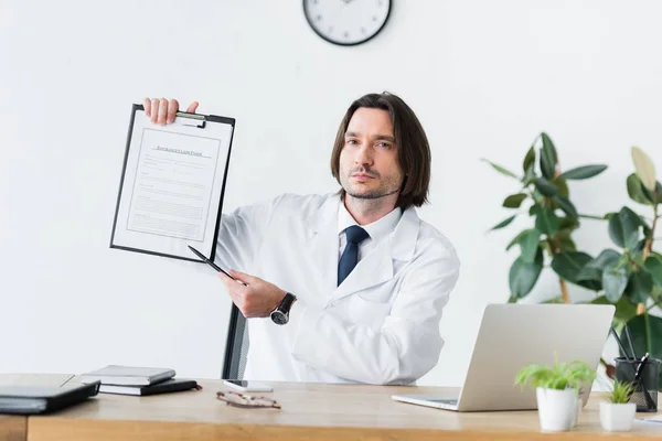 Doctor White Coat Sitting Wooden Table Looking Camera Pointing Pen — Stock Photo, Image