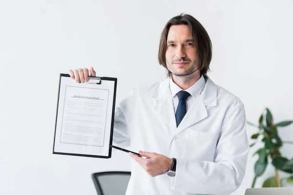 Smiling Doctor White Coat Looking Camera Pointing Pen Medical Document — Stock Photo, Image
