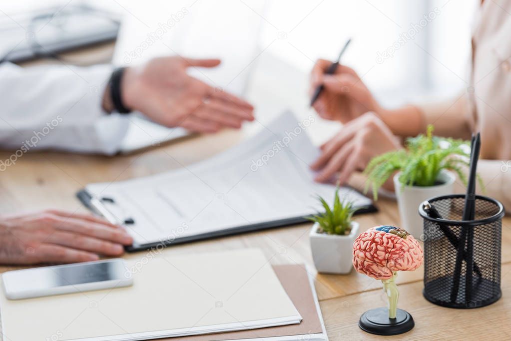 cropped view of doctor with patient signing insurance claim form 