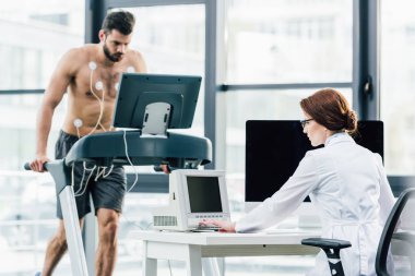 spor salonunda sporcu ile dayanıklılık testi yürüten masada doktor