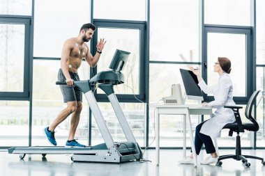 bilgisayar masasında oturan doktor ve spor salonunda sporcu ile dayanıklılık testi yürüten