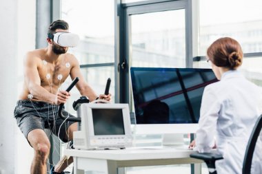 dayanıklılık testi sırasında bilgisayar masasında oturan vr kulaklık ve doktor sporcu