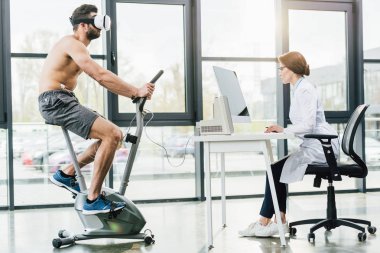 dayanıklılık testi sırasında bilgisayar masasında oturan vr kulaklık ve doktor sporcu
