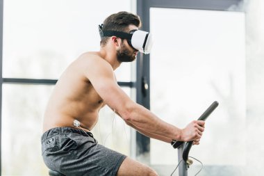 spor salonunda dayanıklılık testi sırasında eliptik elektrotlar eğitim ile Sanal gerçeklik kulaklık gömleksiz sporcu