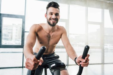spor salonunda eliptik makine üzerinde gülümseyen yakışıklı sporcu eğitimi
