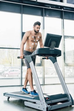 spor salonunda dayanıklılık testi sırasında koşu bandı üzerinde çalışan elektrotlar ile yakışıklı kas sporcu