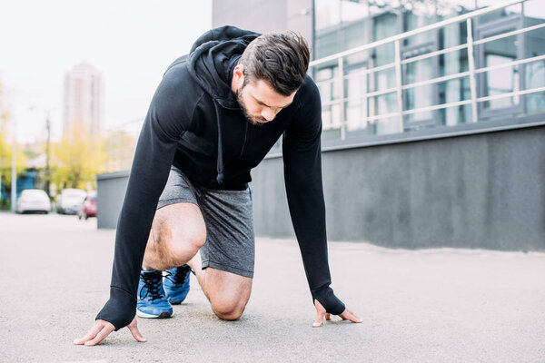 sportsman in hoodie in starting position ready to run 