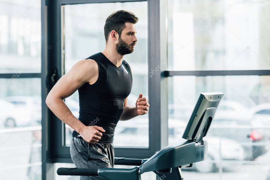 handsome sportsman training on treadmill at sports center