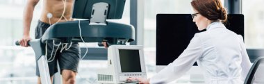 spor salonunda dayanıklılık testi sırasında doktor yakınında koşu bandı üzerinde çalışan sporcunun panoramik atış