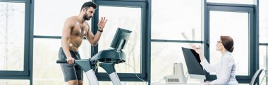 spor salonunda dayanıklılık testi sırasında doktor yakınında koşu bandı üzerinde gesturing sporcu panoramik atış