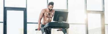 spor salonunda dayanıklılık testi sırasında koşu bandı üzerinde çalışan elektrotlar ile yakışıklı sporcunun panoramik atış