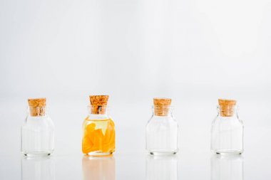 glass corked jar with essential oil with orange slices near empty jars on white background clipart