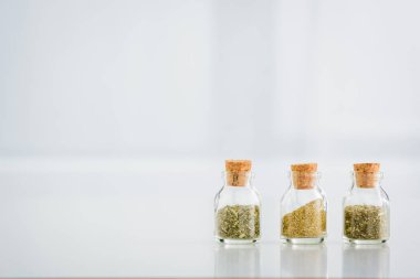 corked jars with dried herbs on white background with copy space clipart