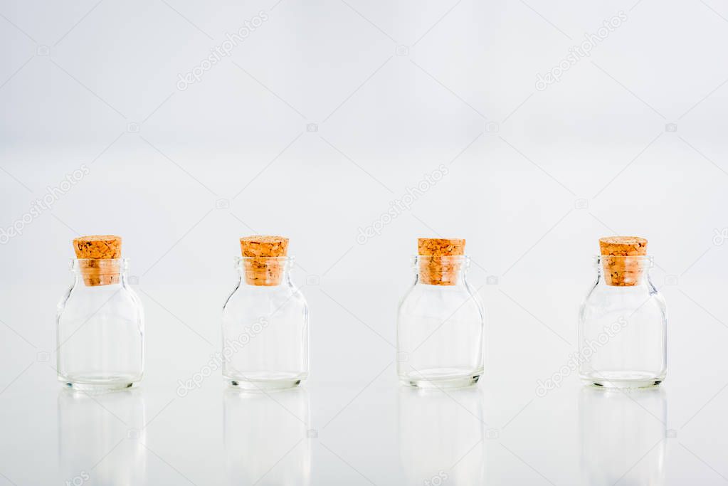 empty corked glass jars on white background with copy space