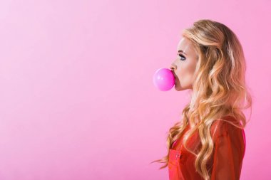 side view of beautiful girl blowing bubble gum on pink, doll concept clipart
