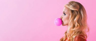 panoramic shot of beautiful girl blowing bubble gum isolated on pink, doll concept clipart