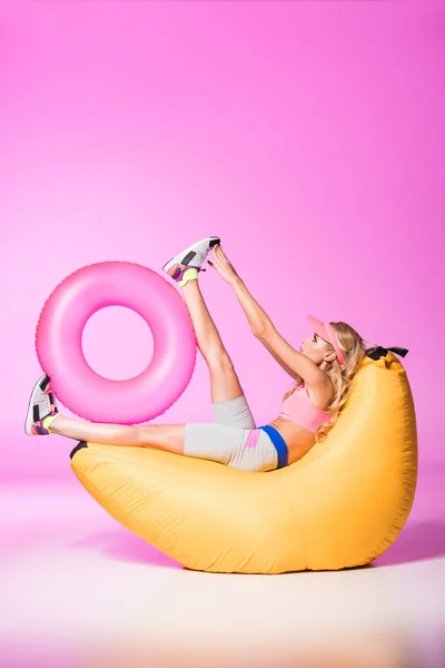 ピンクの上に水泳リングと豆袋椅子の魅力的な女の子 人形のコンセプト — ストック写真