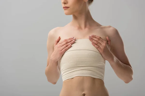 灰色で隔離された胸の包帯を持つ女性のトリミングされたビュー — ストック写真