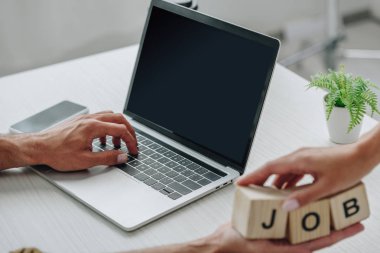 dizüstü bilgisayar kullanarak kadın ve erkeğin kısmi görünümü ve yazı işi ile küpleri tutma 