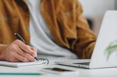 cropped view of man writing in notebook with pen  clipart